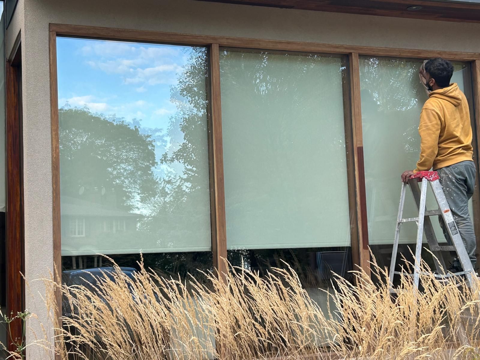 A man is standing on a ladder cleaning a window.