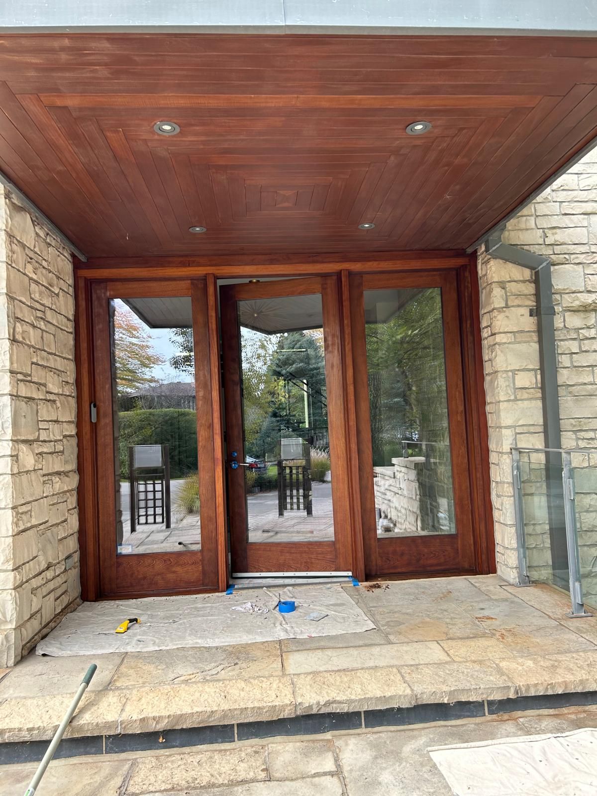 The front door of a house with a wooden ceiling and sliding glass doors.