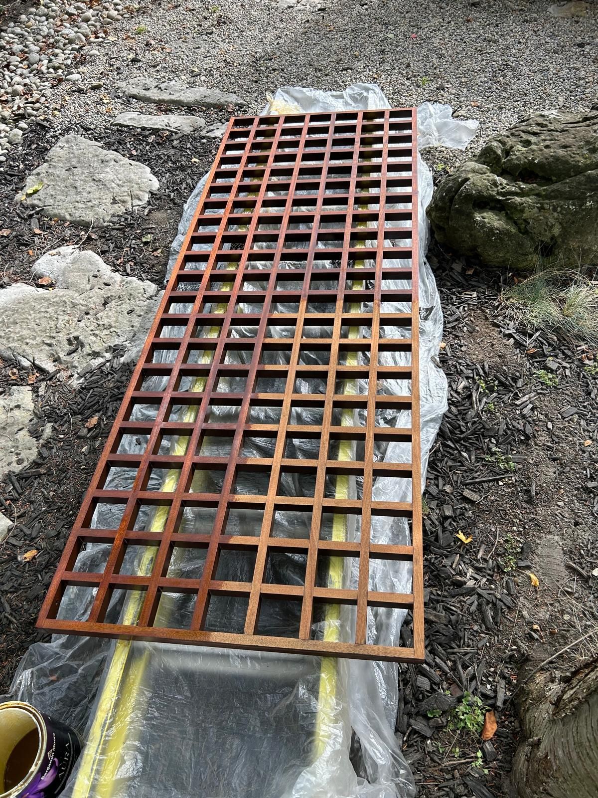 A wooden trellis is sitting on top of a ladder on the ground.