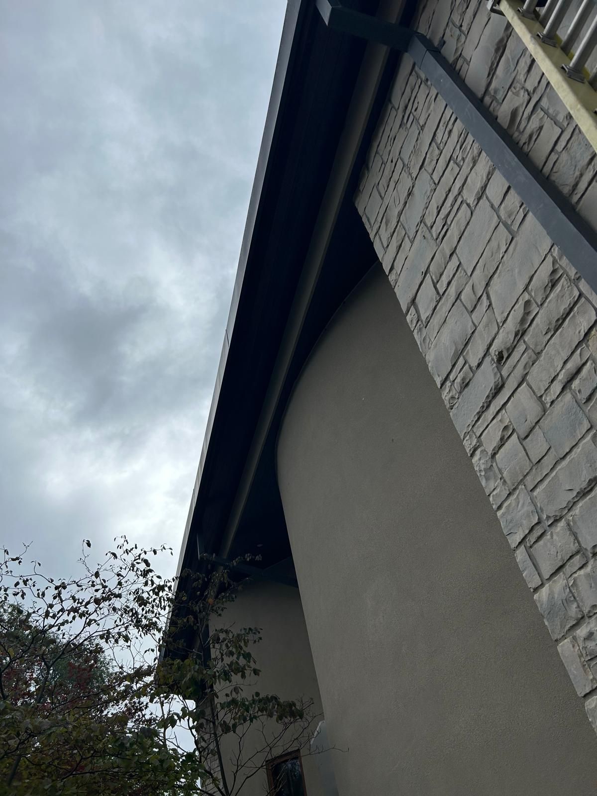 Looking up at the roof of a building with a cloudy sky in the background.