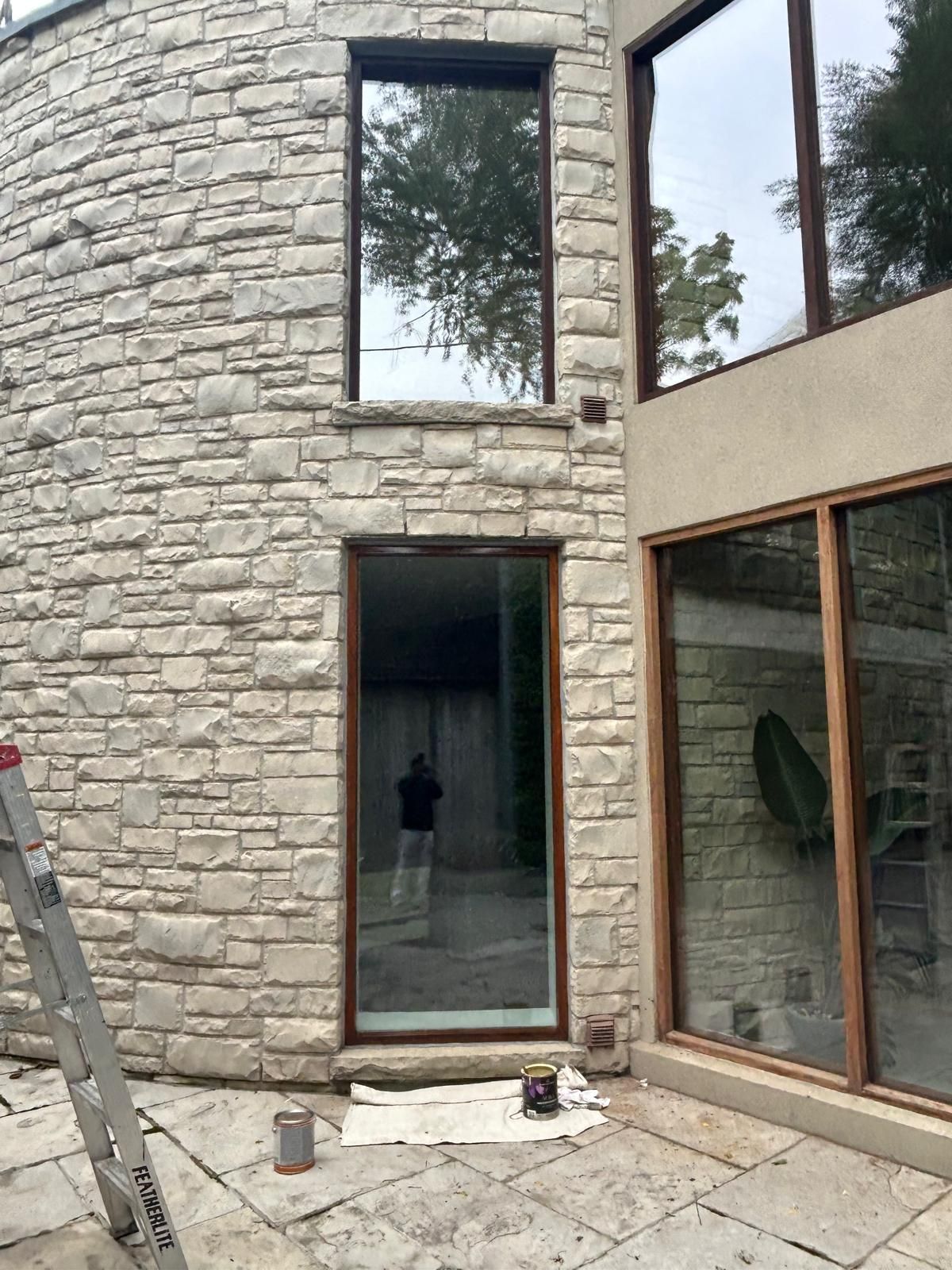 A ladder is sitting in front of a brick building with a lot of windows.