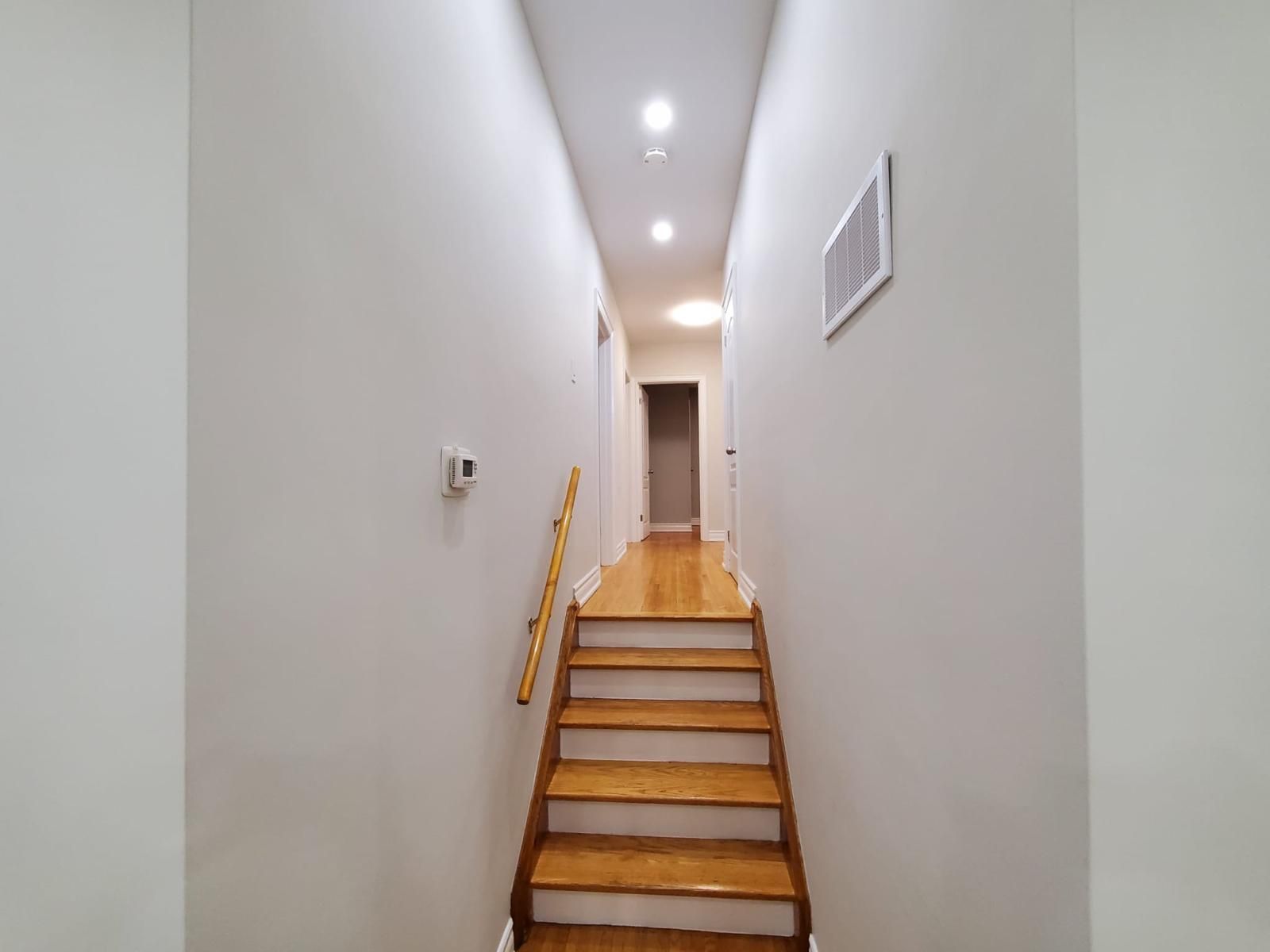 A long hallway with stairs leading up to the second floor of a house.
