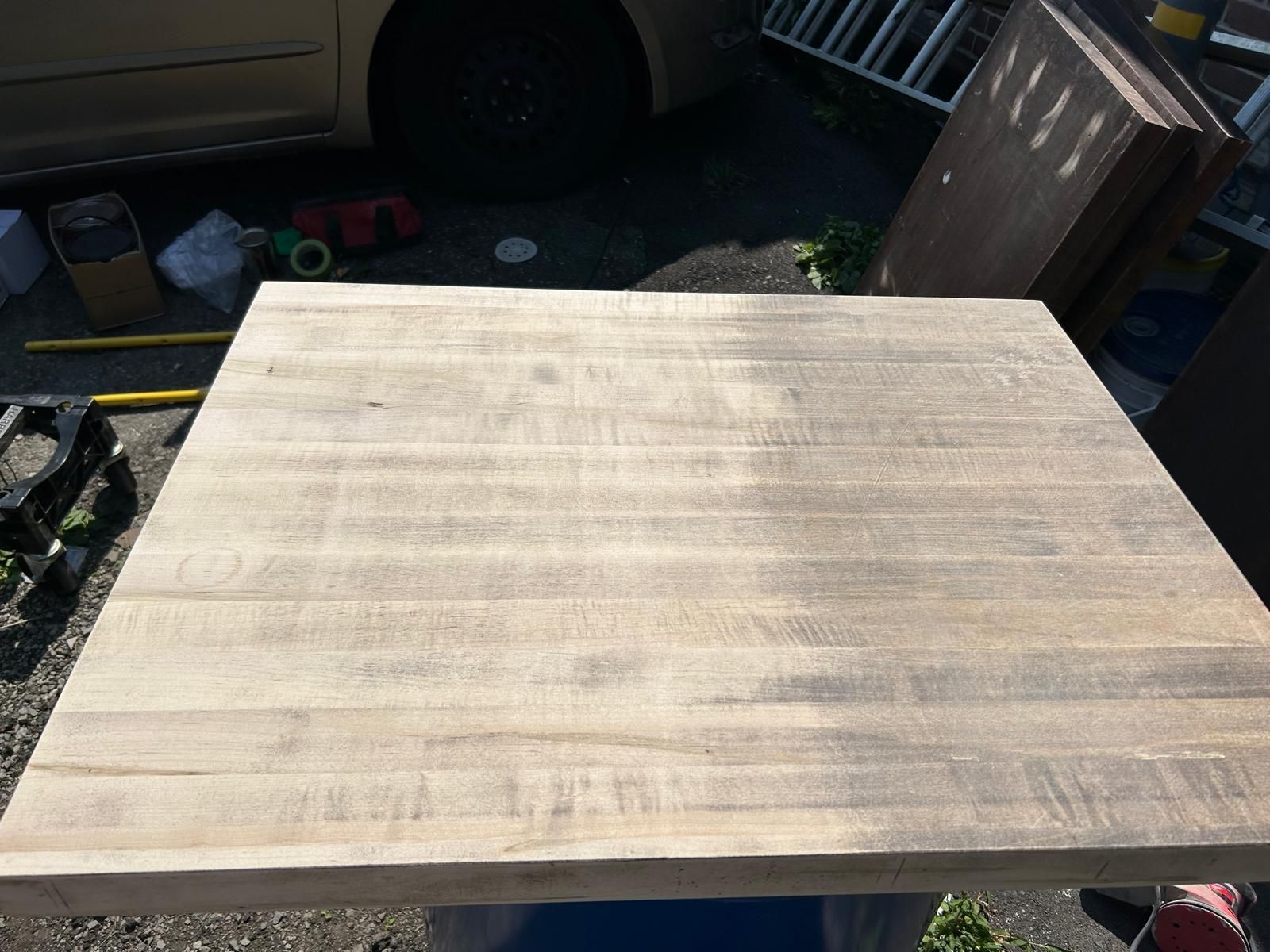 A large piece of wood is sitting on the ground in front of a car.
