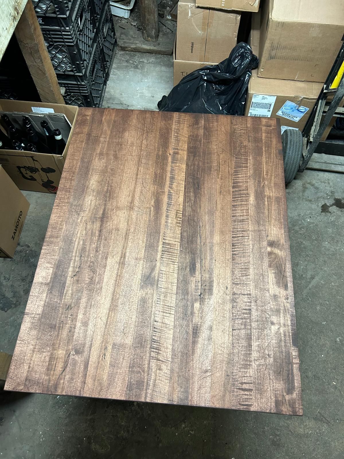 A wooden table is sitting in a garage next to boxes.
