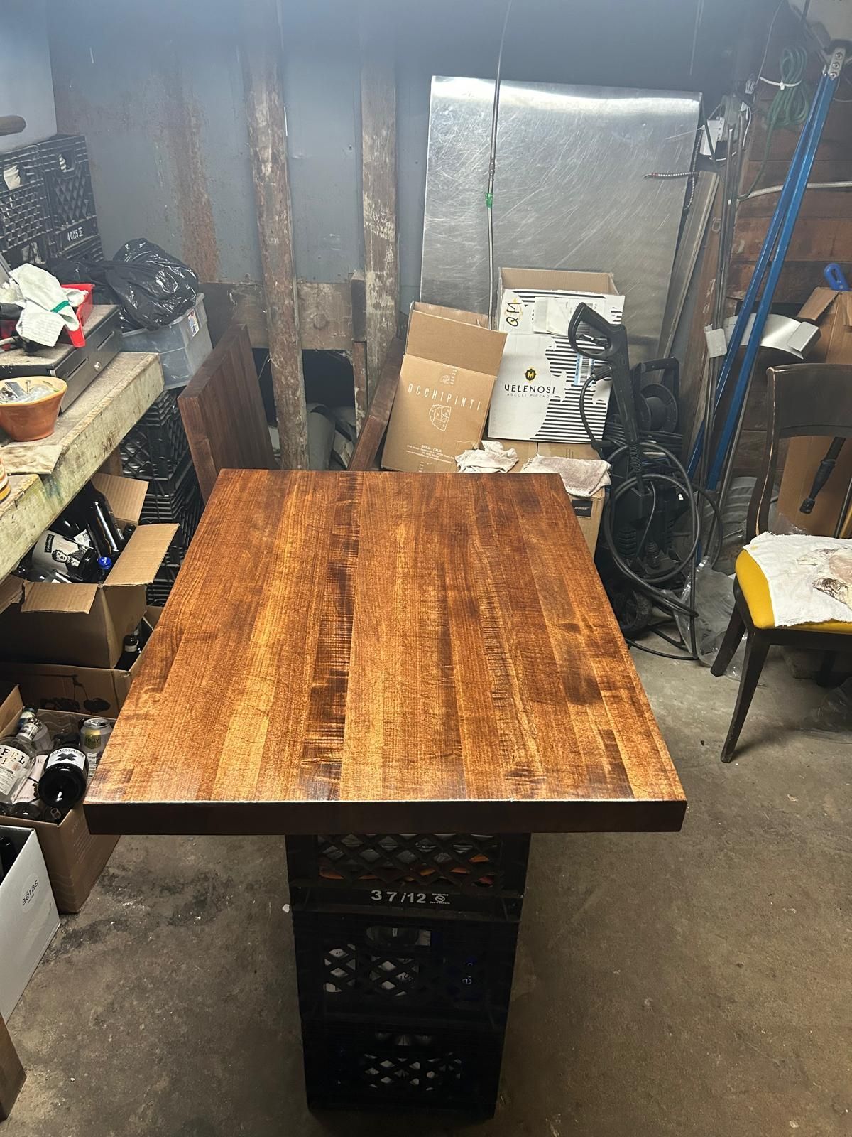 A wooden table is sitting in a room filled with boxes.