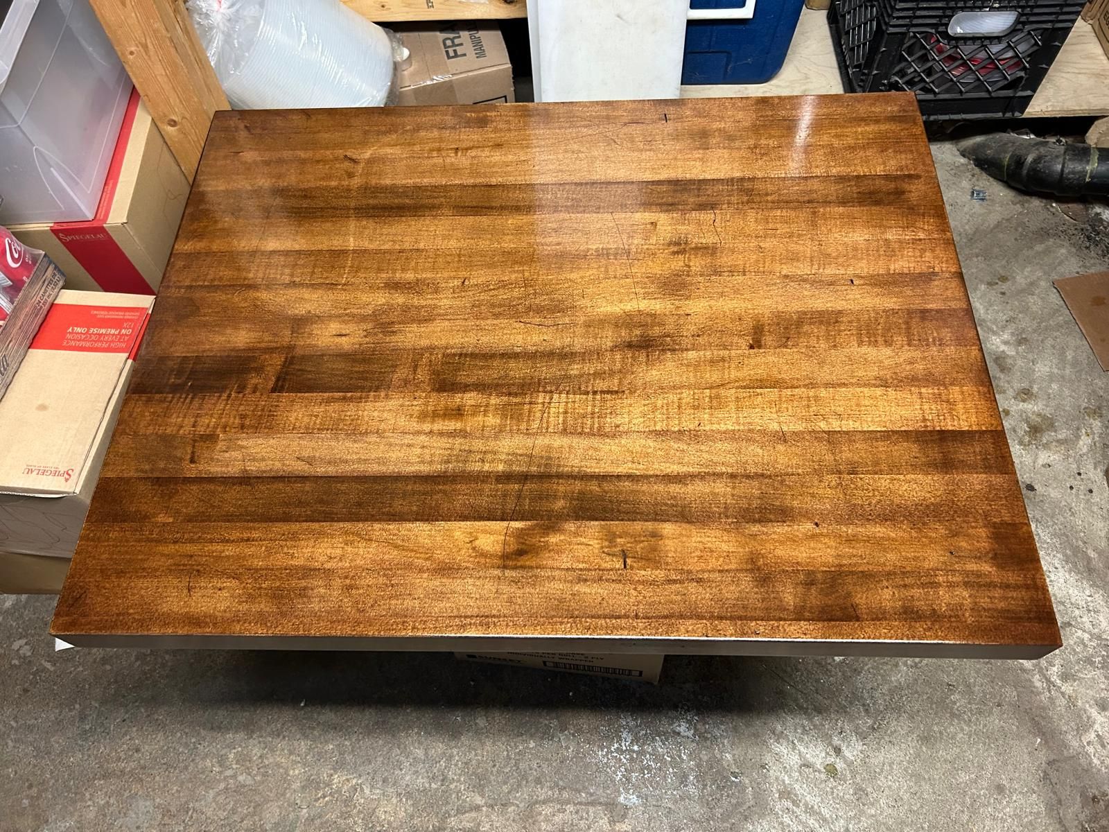 A wooden table is sitting on top of a concrete floor.