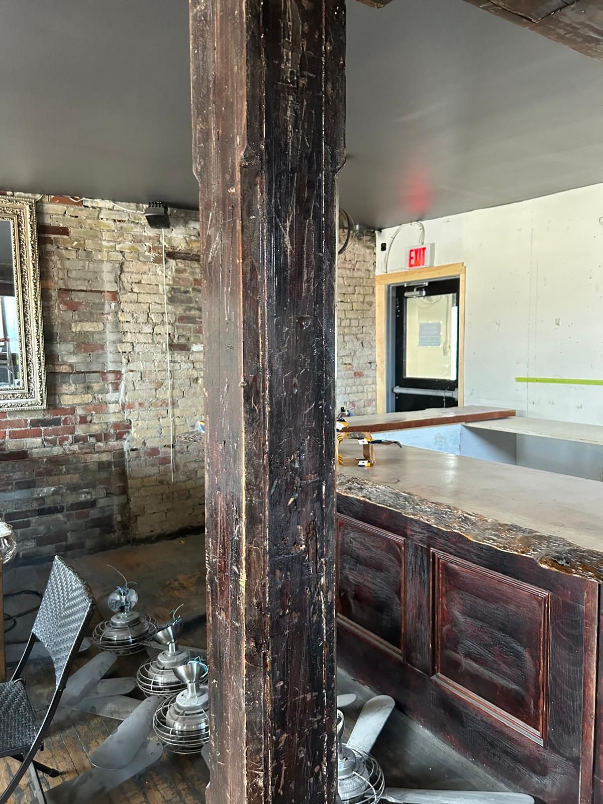 A room with a brick wall and a wooden pillar in the middle of it.