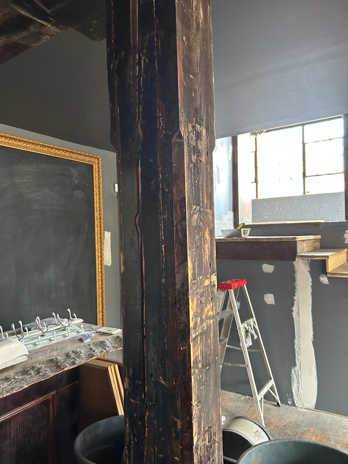 A ladder is sitting next to a wooden post in a room.
