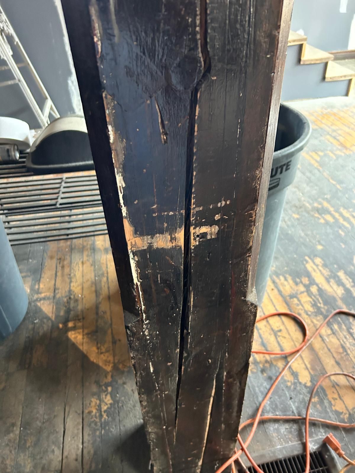 A close up of a wooden post with a trash can in the background