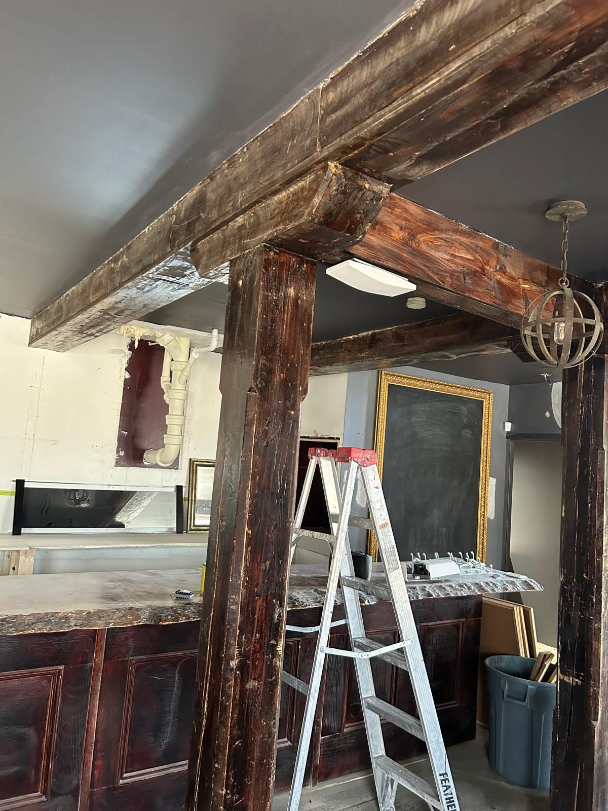 A ladder is sitting under a wooden beam in a room.