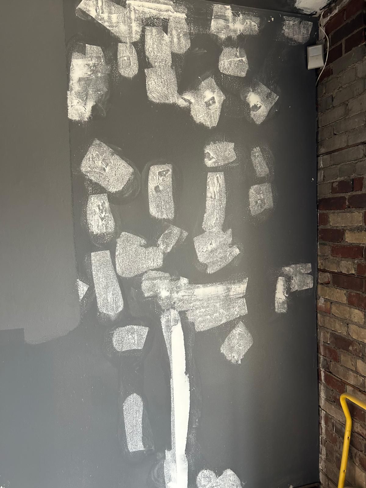 A wall with a lot of white paint on it and a brick wall behind it.