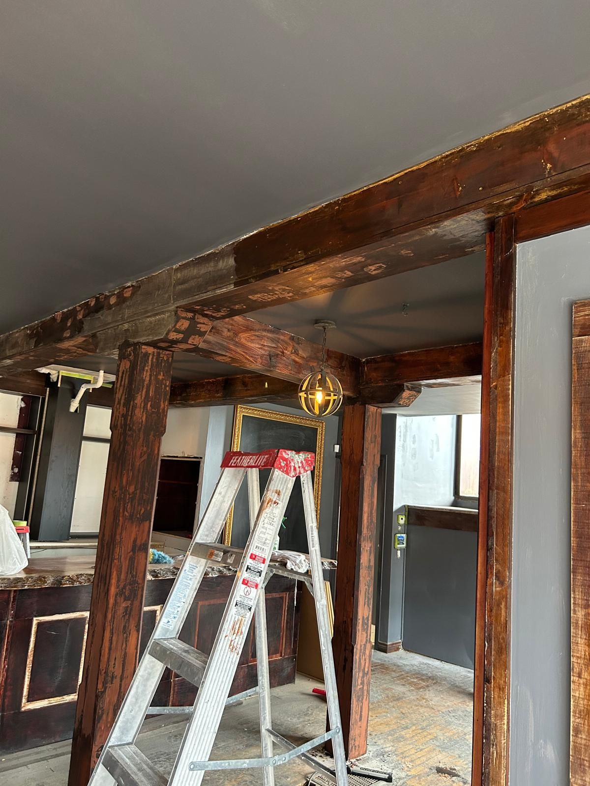 A ladder is sitting under a wooden beam in a room.
