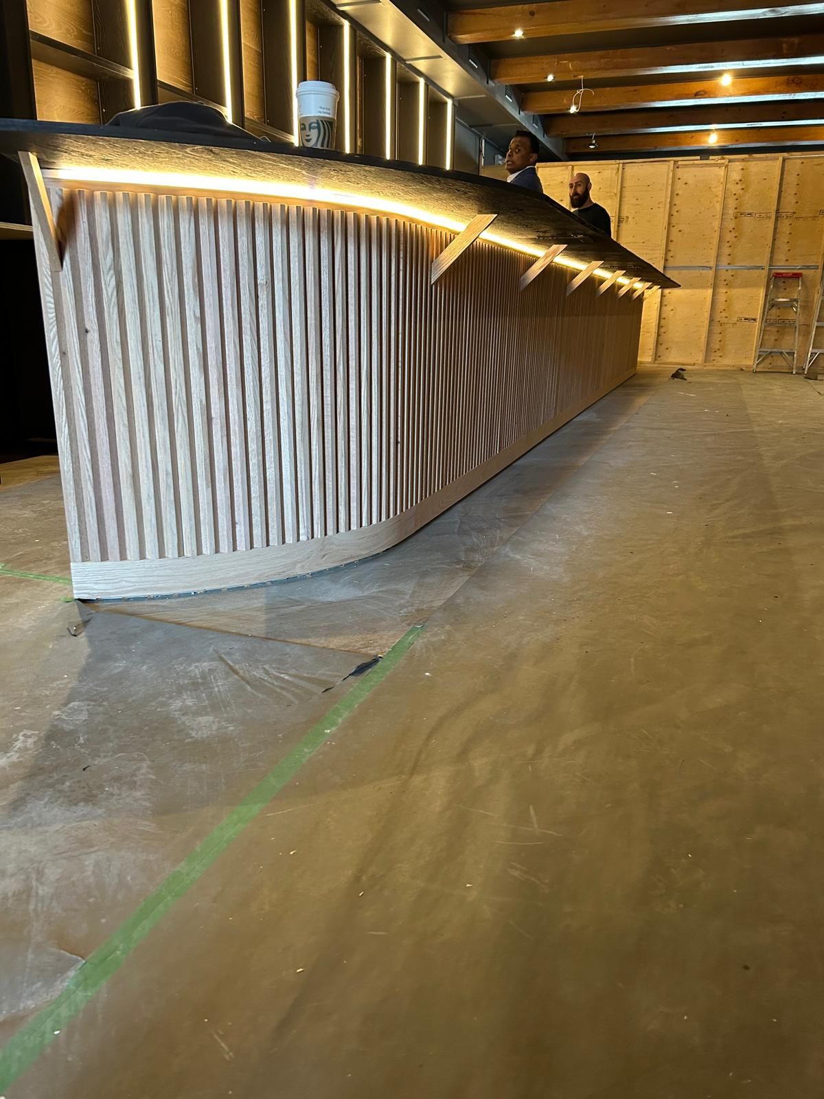 A long wooden counter in a room with two men standing behind it.