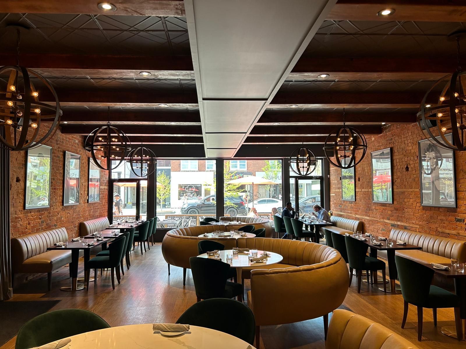 A large dining room with tables and chairs and a brick wall.