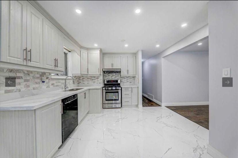 A kitchen with white cabinets , stainless steel appliances , and a marble floor.