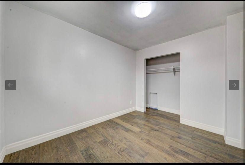 An empty bedroom with hardwood floors and a closet.