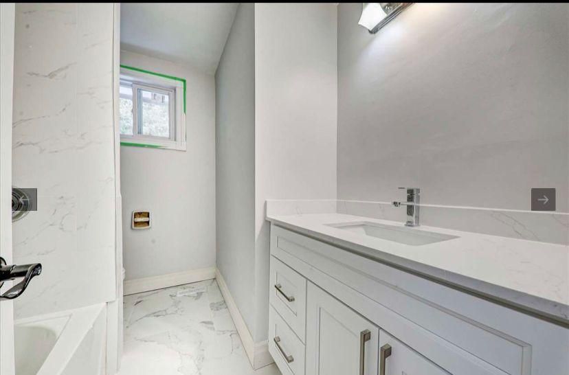 A bathroom with a sink , tub and mirror.