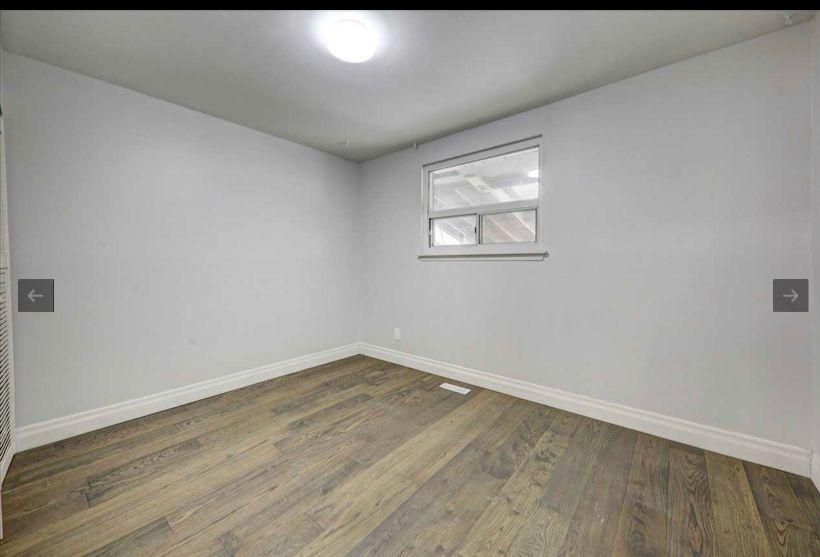 An empty room with hardwood floors and a window.