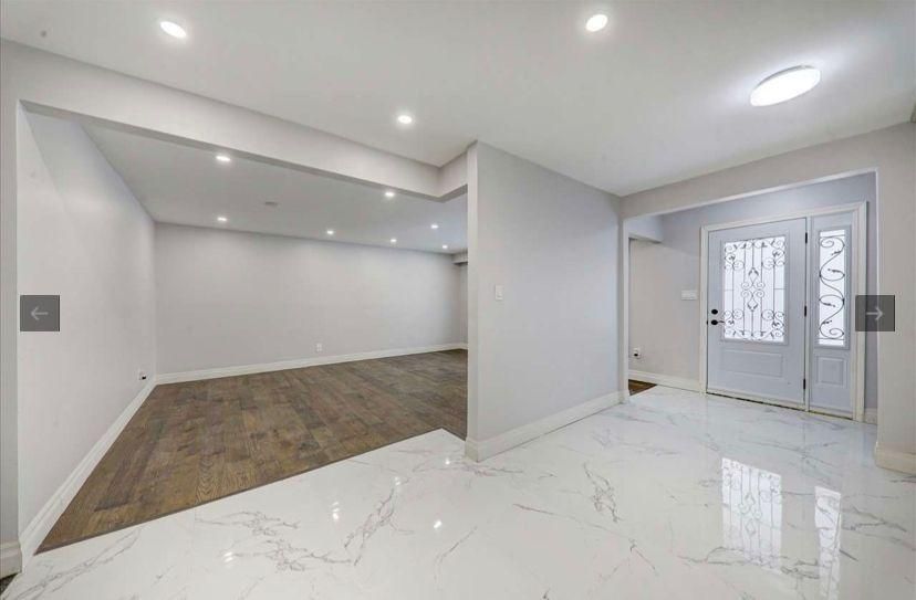 A large empty room with a marble floor and a door.