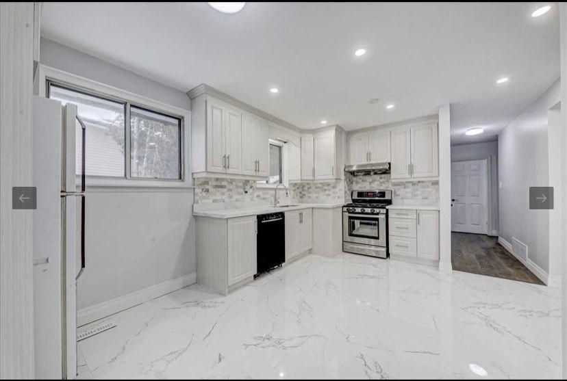 A kitchen with white cabinets , stainless steel appliances , and a marble floor.