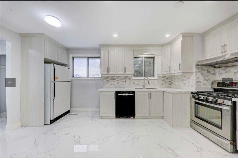 A kitchen with white cabinets , a stove , a refrigerator , and a dishwasher.