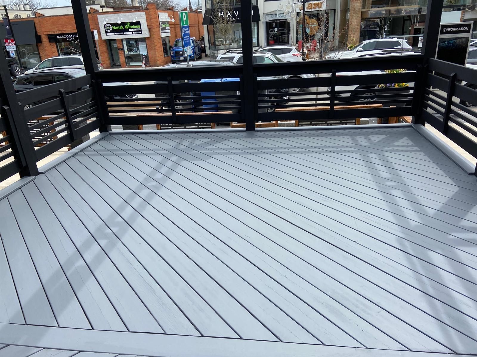 A balcony with a gray deck and a black railing