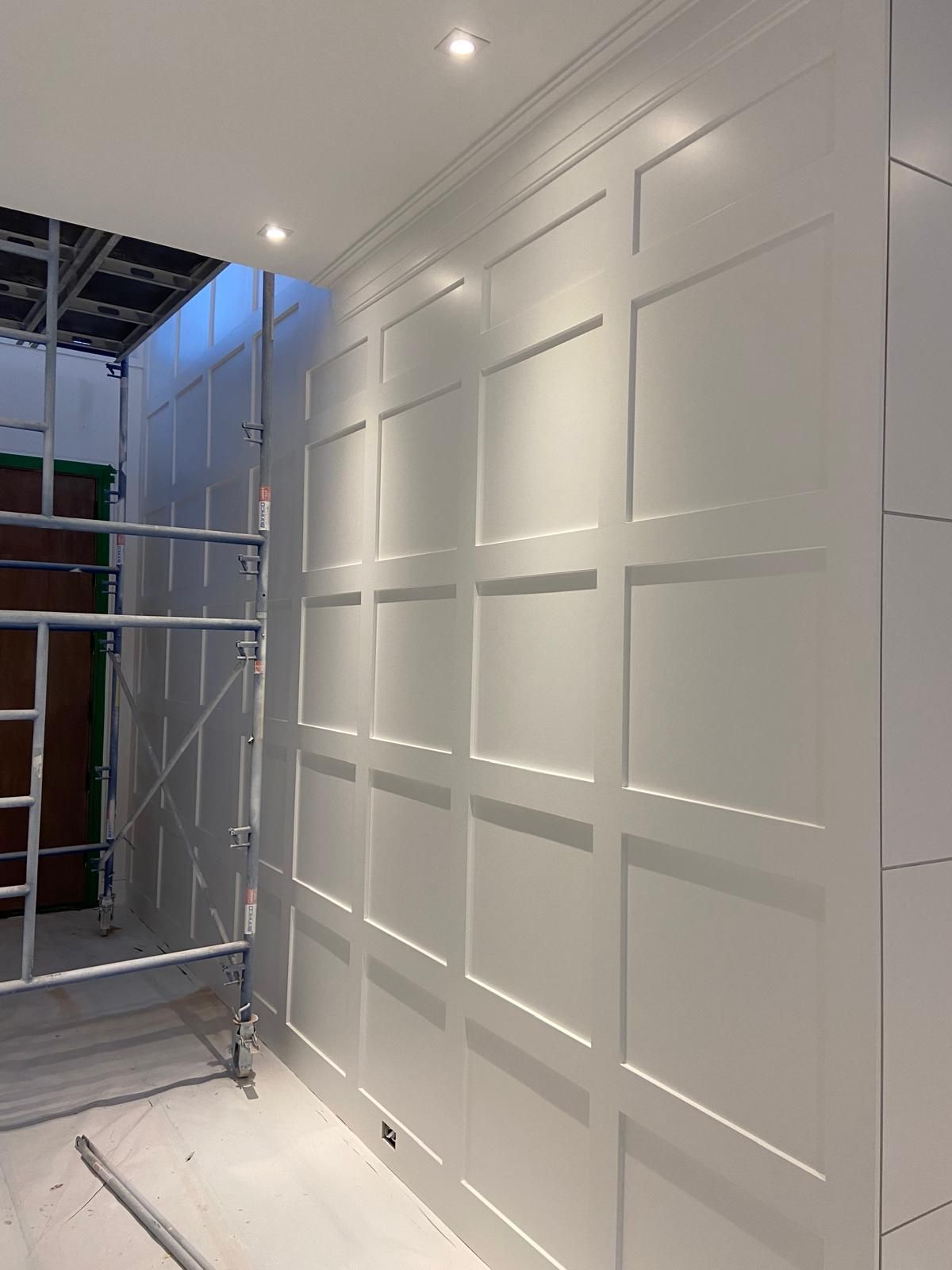 A white wall with a ladder and scaffolding in a room.