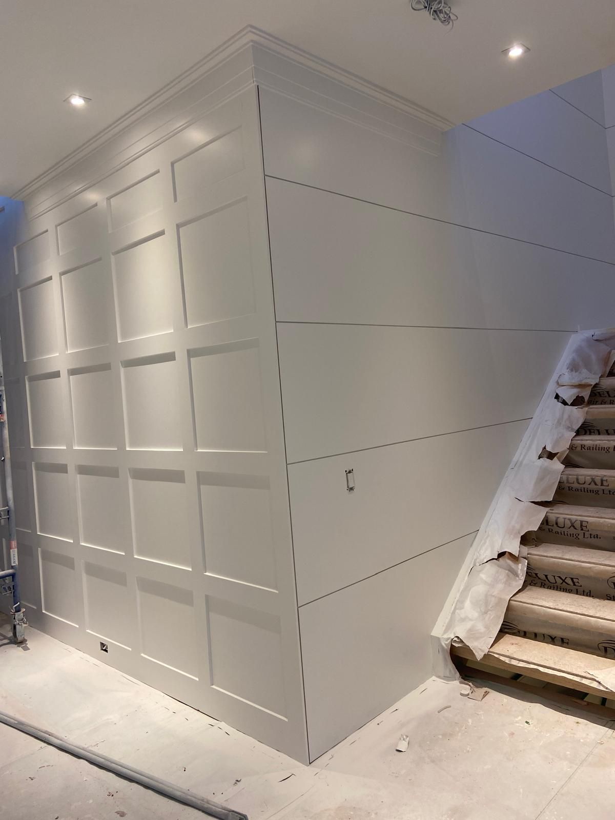 A white wall with a staircase in the background.