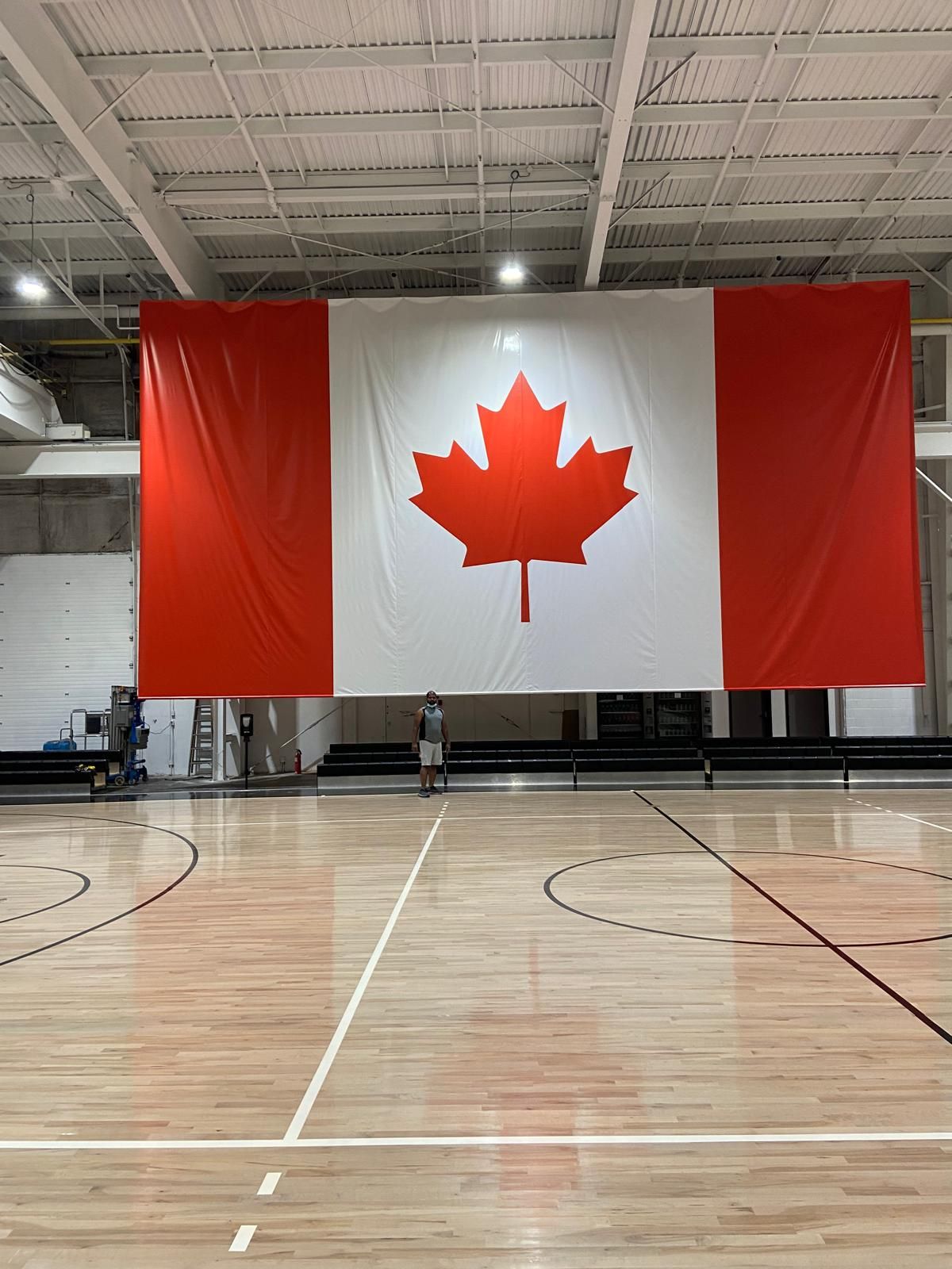 A large canadian flag is hanging on the wall of a gym.