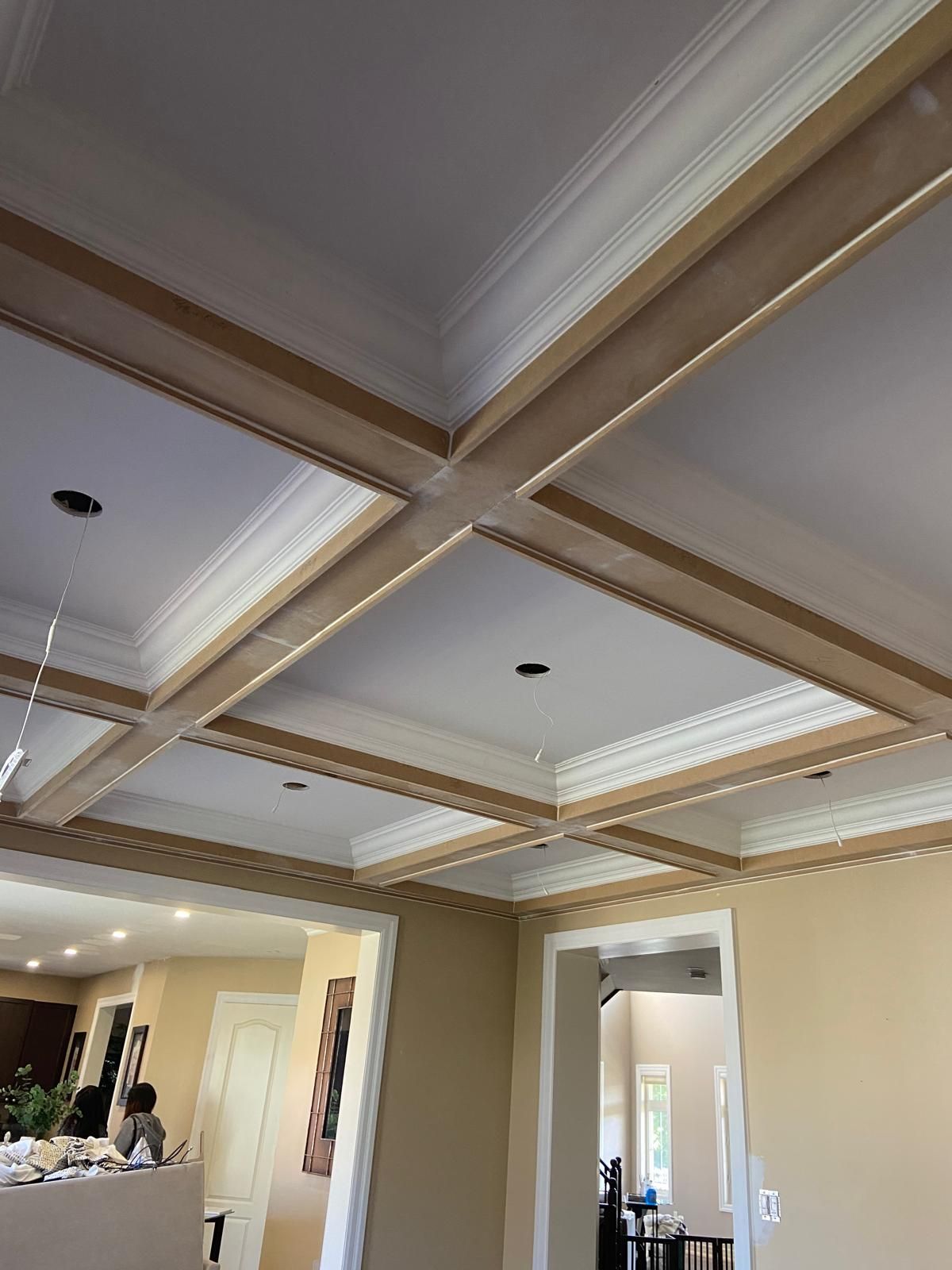 A living room with a coffered ceiling and a dining room in the background.