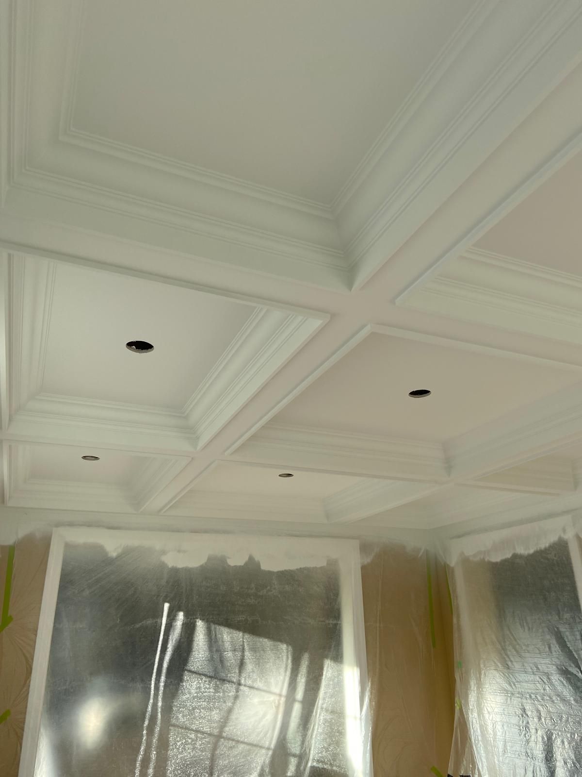 The ceiling of a room is being painted white.