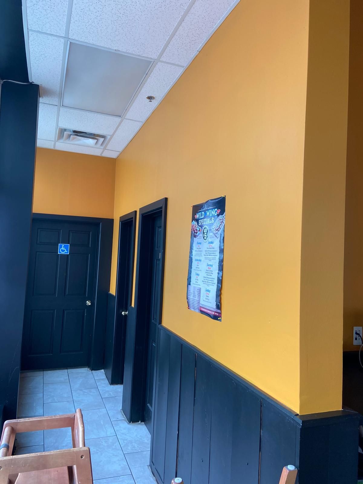 A hallway with yellow walls and black trim in a restaurant