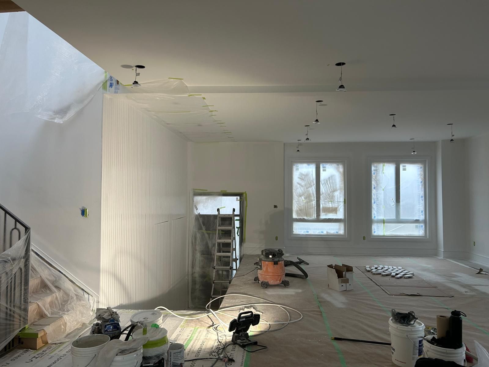 A room that is being painted with a lot of tools on the floor