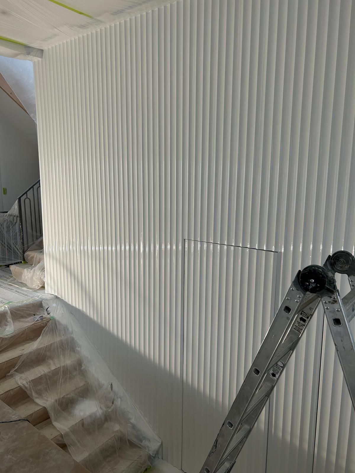 A ladder is sitting in front of a white wall.