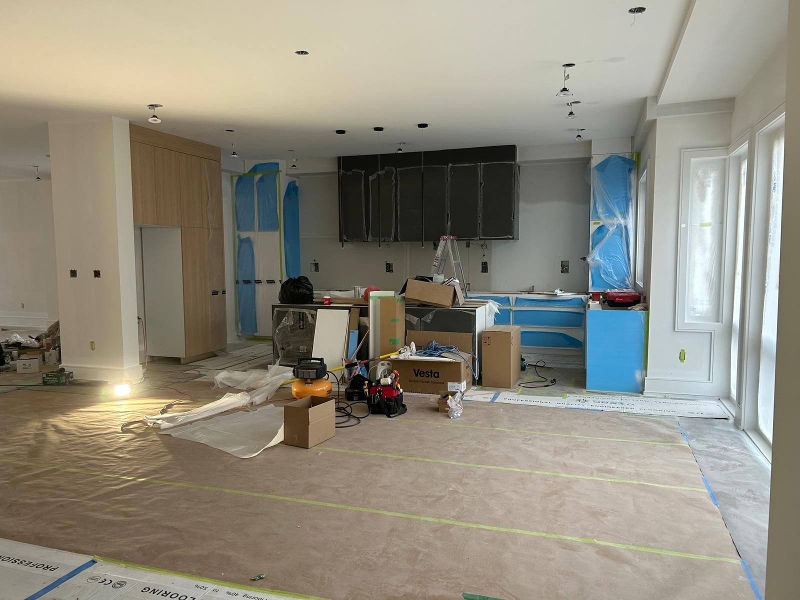 A large room with a lot of furniture and boxes in it is being remodeled.