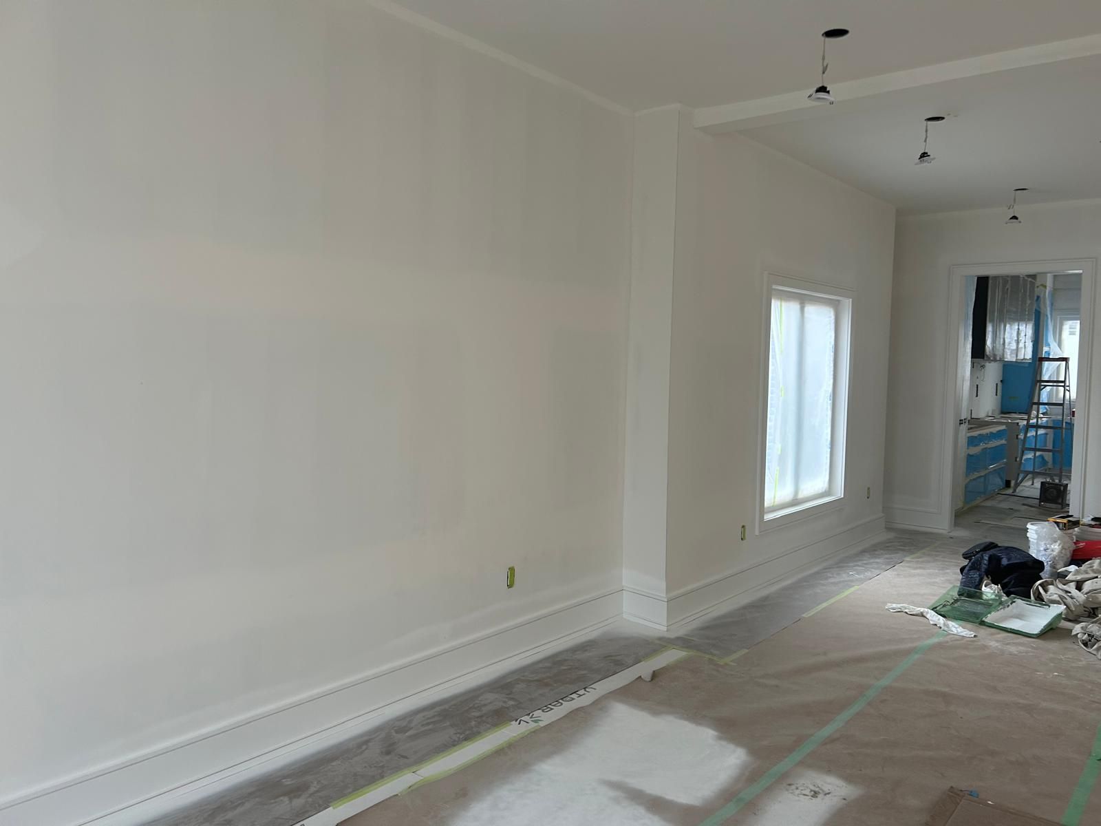 A room with a lot of white walls and a lot of windows is being painted.