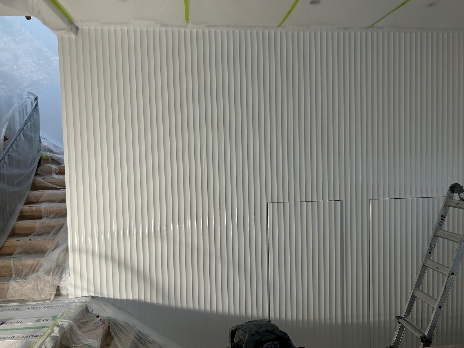 A room with a white wall and a ladder in it.