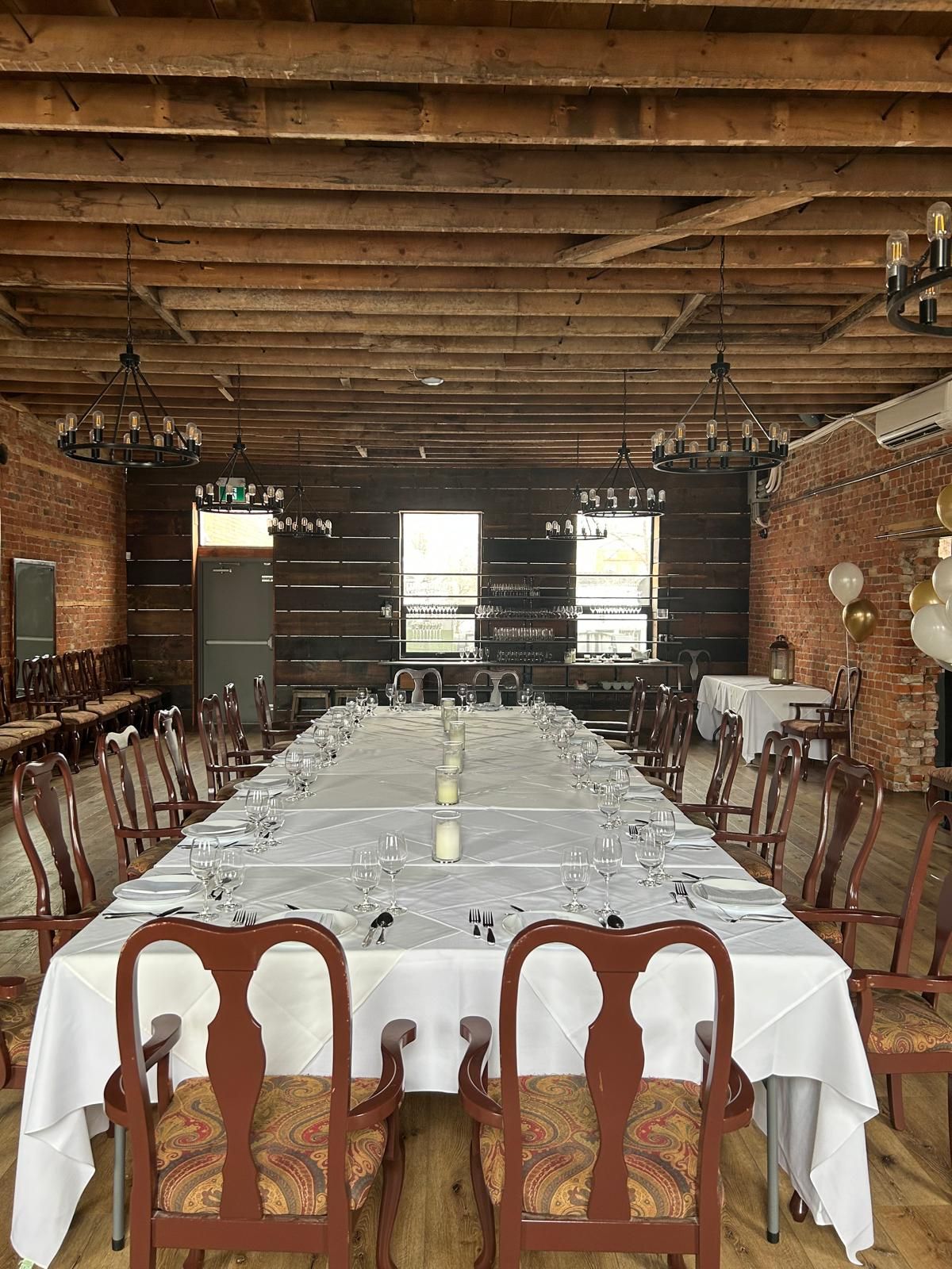 A long table with a white tablecloth and chairs in a large room.