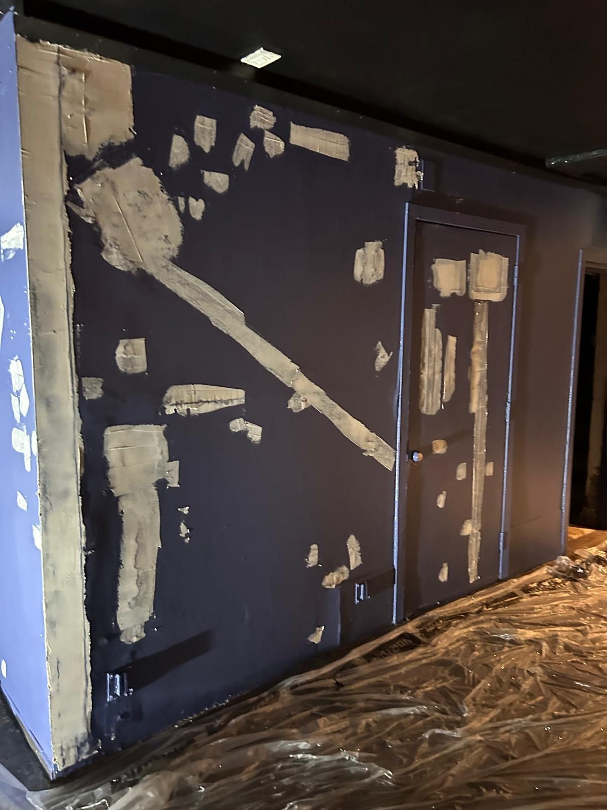 A room with a blue wall and a door covered in plastic.