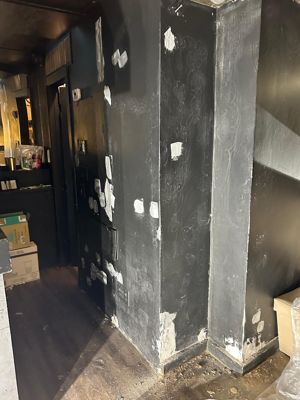 A corner of a room with black walls and a wooden floor.