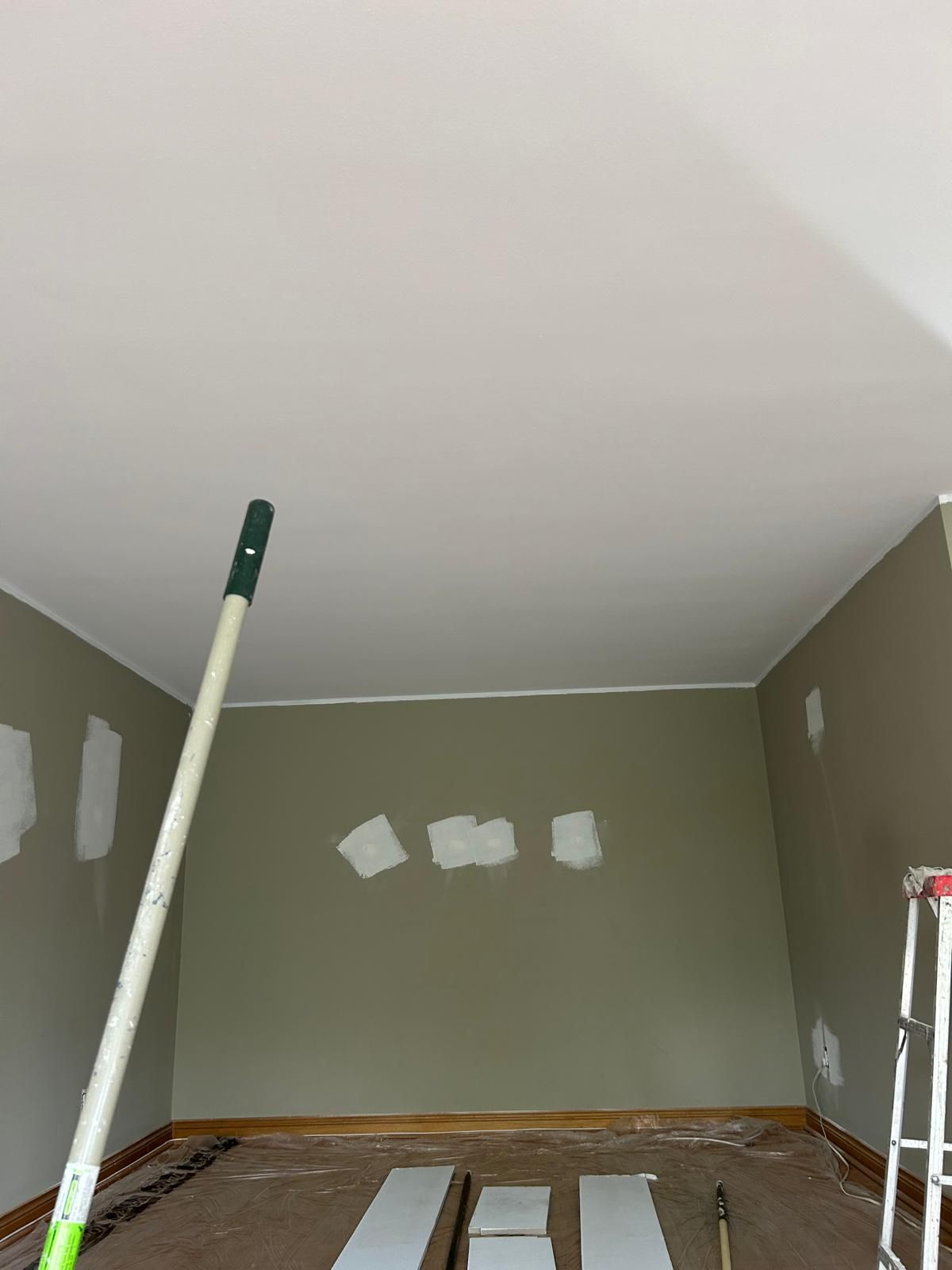 A room with a ladder and a mop in it is being painted.