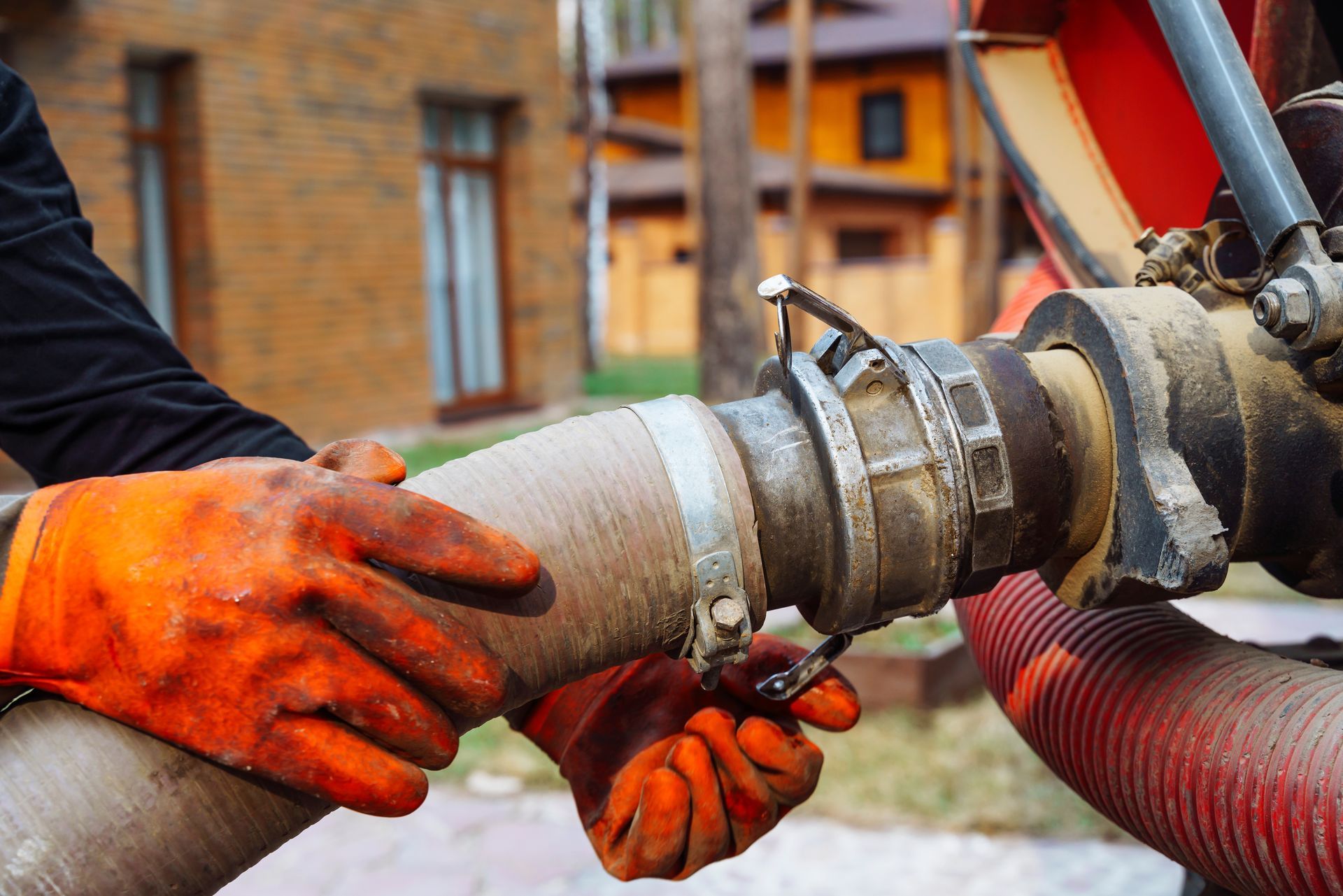 a hand connects a suction hose to a sewage tanker truck.