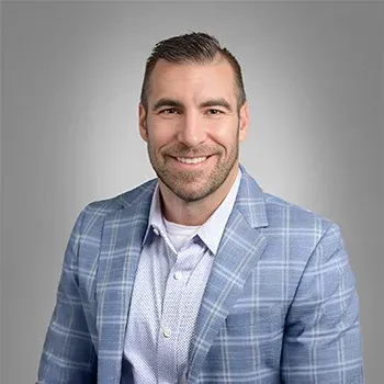 Man in blue plaid blazer smiles, with a light gray background.