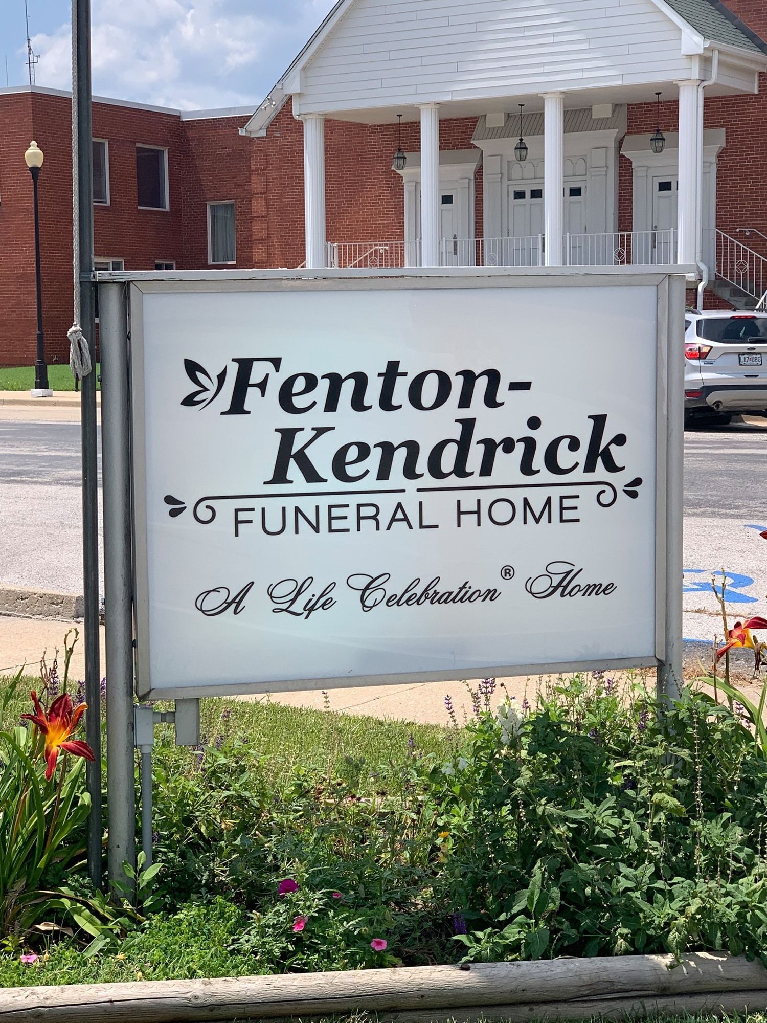 Fenton-Kendrick Funeral Home sign in front of a brick building and landscaped flowers