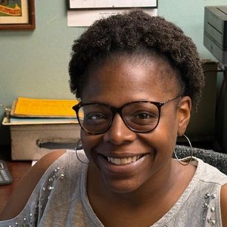 A woman wearing glasses and hoop earrings is smiling for the camera.