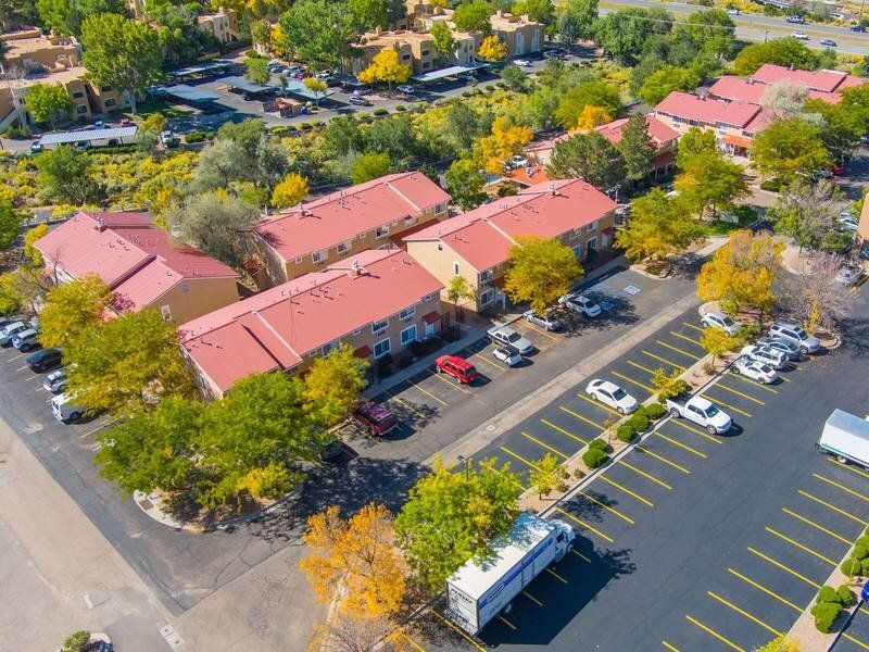 Aerial view of a multi-building apartment complex with red roofs, parking lots, and trees at Santa Fe Suites in Santa Fe, NM.