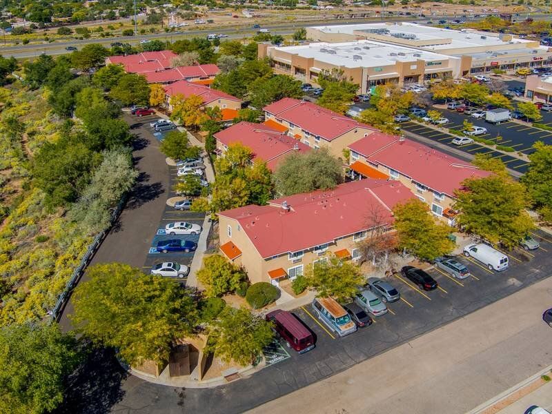 Aerial view of a multifamily community with red-roof buildings and surrounding trees at Santa Fe Suites in Santa Fe, NM.