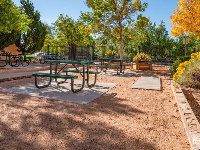 Outdoor community picnic area with green metal tables and benches at Santa Fe Suites in Santa Fe, NM.