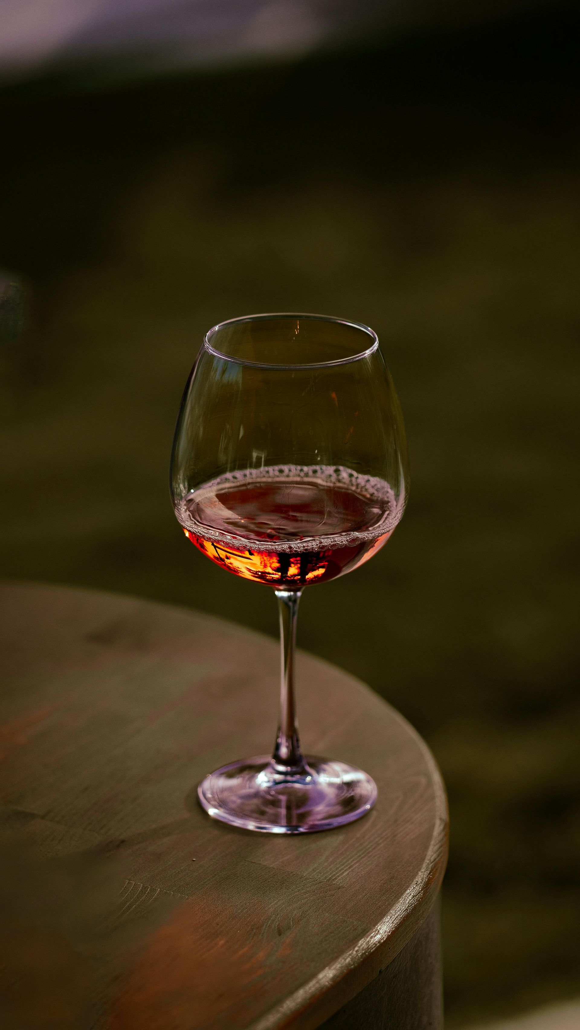 A glass of wine is sitting on a wooden table