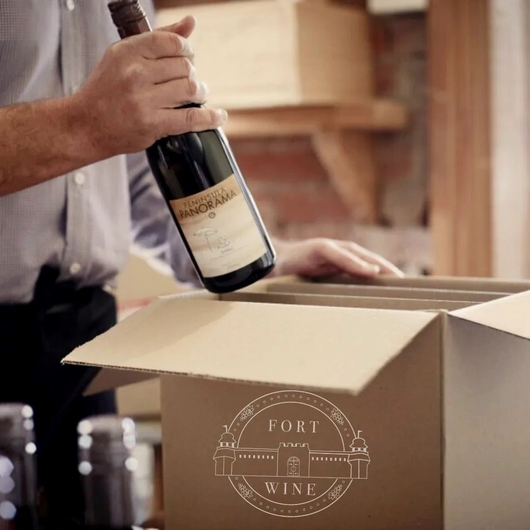 A man is putting a bottle of wine into a box that says fort wine